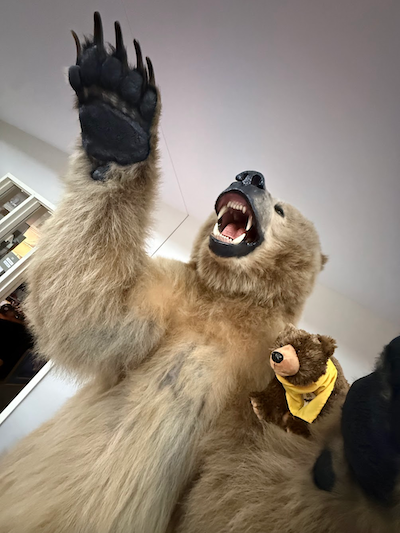 Taxidermied Alaskan brown bear on his hind legs with his teeth bared, with a small stuffed animal brown bear perched on his shoulder