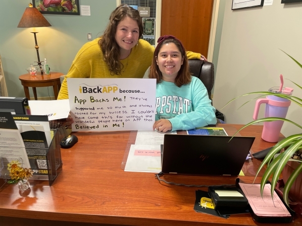 Library staff member Andrea Tester with library student employee Ivy Herrera holding an iBackAPP sign