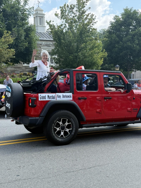 Photograph of Kay Borkowski in a red Jeep as Grand Marshall