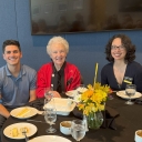 Photograph of male student in blue shirt, scholarship donor woman in red blazer, library personnel woman in black shirt with name tag
