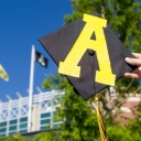 Hand holding up a graduation cap with an App State 