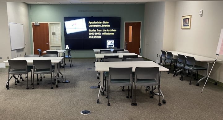 Space has a large visualization wall, several four-seat tables, and wall space for exhibits and book displays