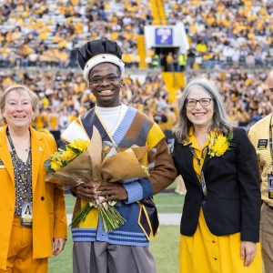 Provost Neva Spect, Bright Uwakwe, Chancellor Heather Norris, Dr. JJ Brown in black and gold on the Appstate Football field awarding, Bright the King of the Rock Crown and Honor
