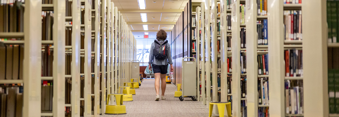 student walking through Belk Library stacks