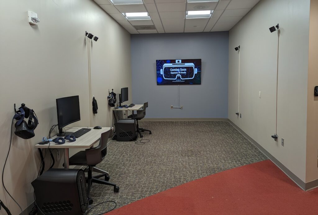 Virtual Reality Studio showing two individual workstations and a large wall-mounted display