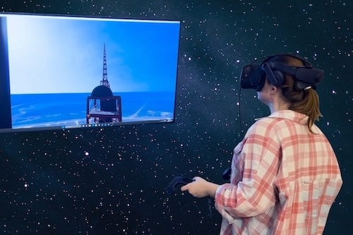Student in VR headset playing game that is mirrored on external display
