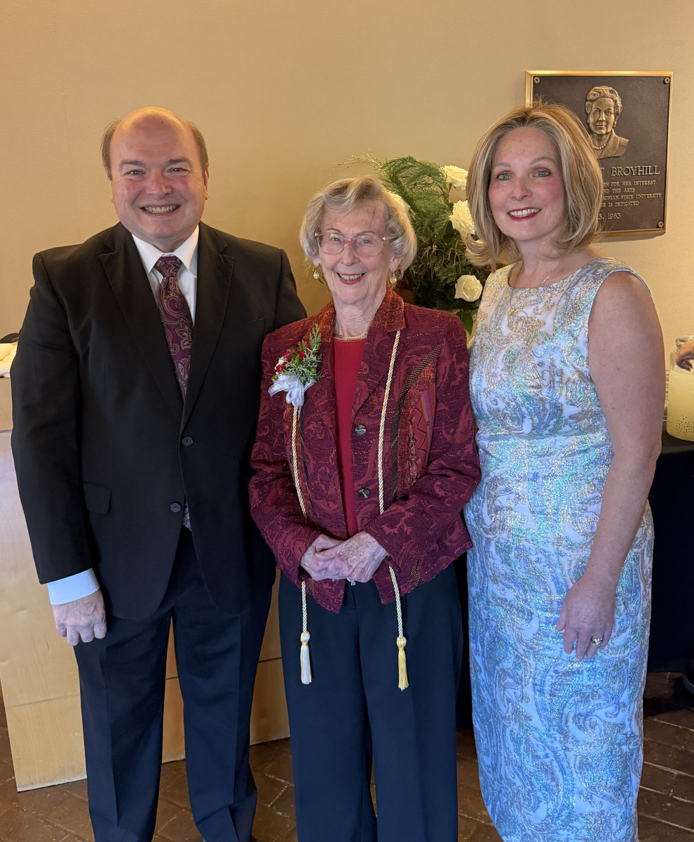 Barbara Freiman, wearing honor cords and smiling, stands between Dr. James Douthit, Dean Sue Polanka, 