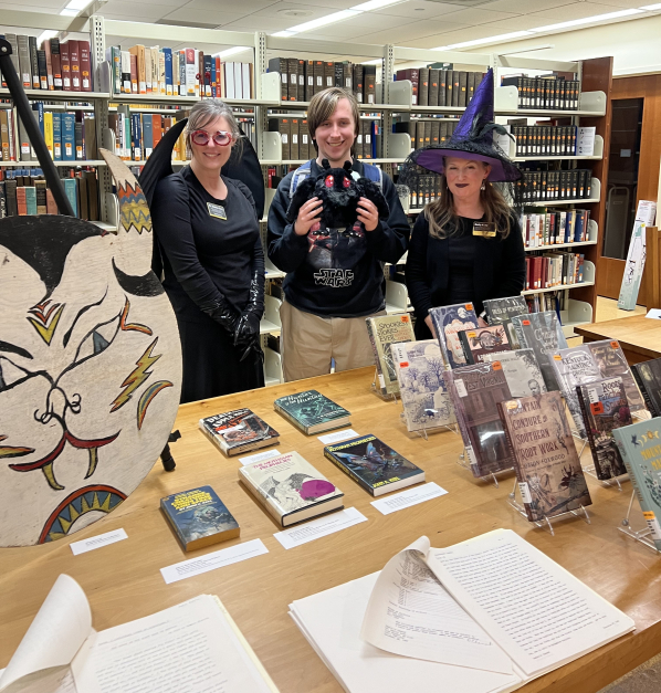 Jessica Cory dressed as a mothmaiden, ghost story contest winner Kanai Peeples with Mothman stuffie, and Emily Kader dressed as a a witch