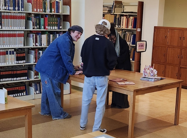 Artist and students observing a pop up book open on a table in the SCRC